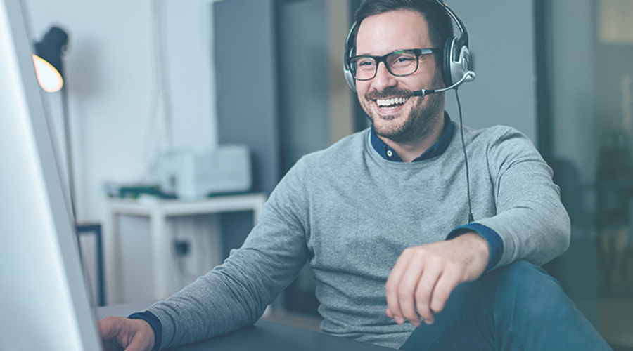 Image of Man smiling at laptop with headphones
